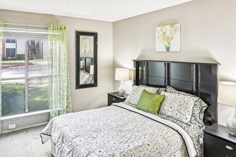 Model apartment bedroom with a bed and a large window at Hunters Chase in Austin, TX